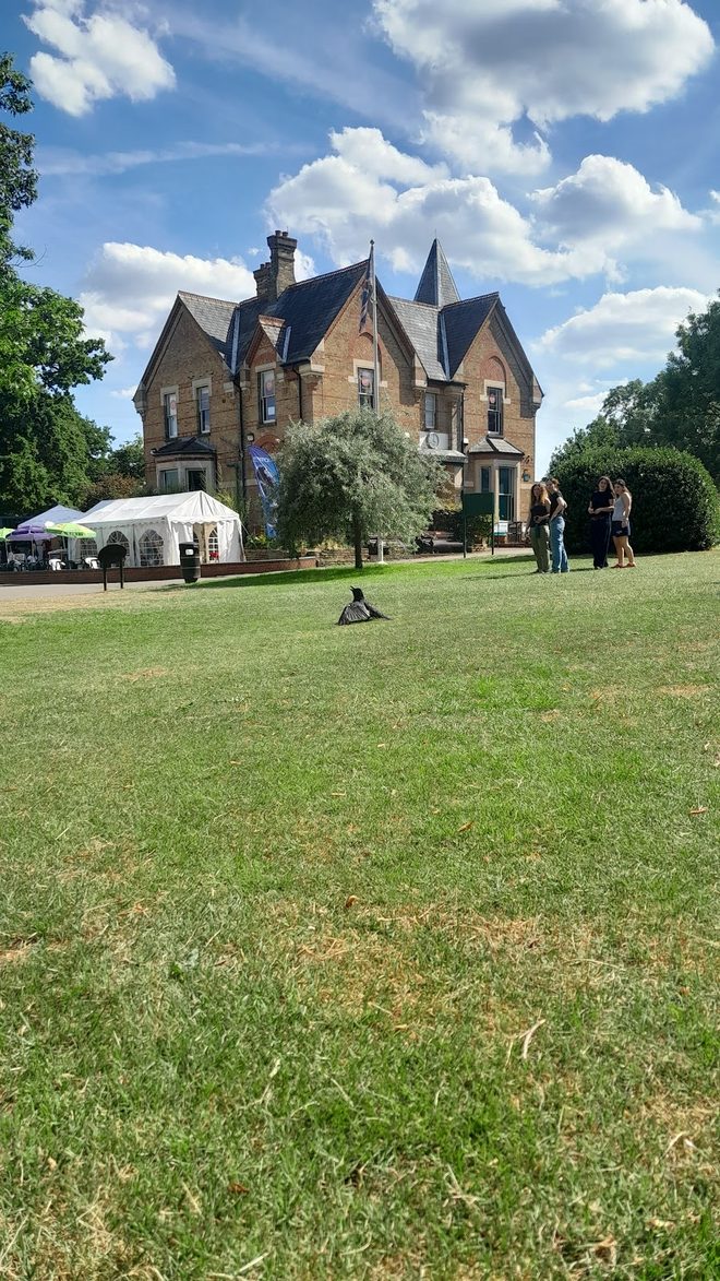 The Victorian Friary House across a wide sunlit lawn with a white marquee beside it